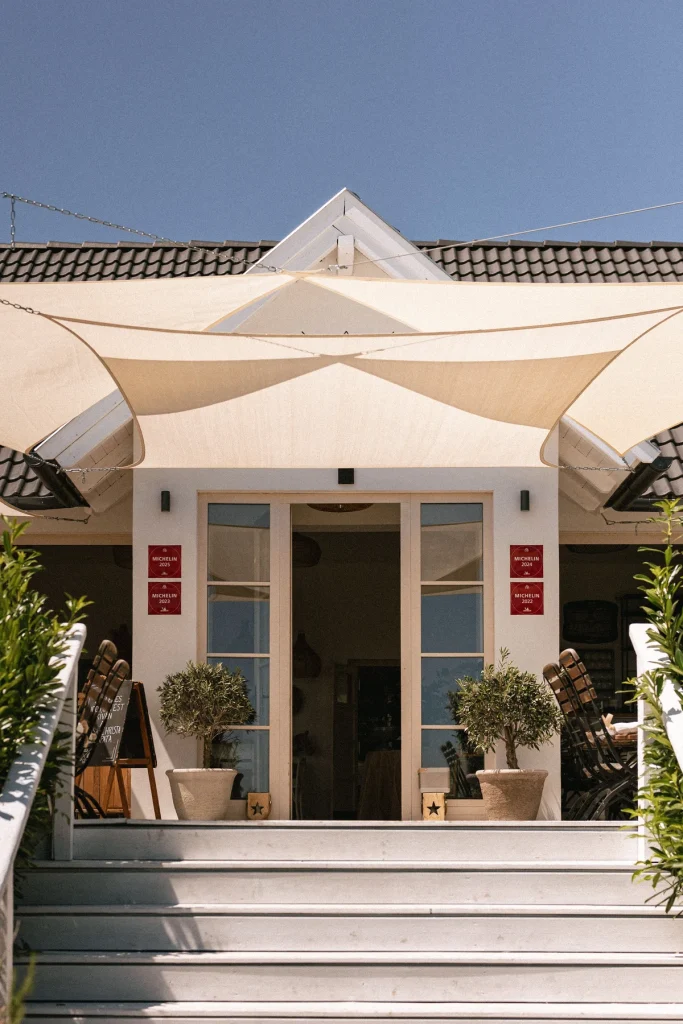 Der Eingang zum Casa Christa Restaurant mit Schattensegeln und Michelin Awards