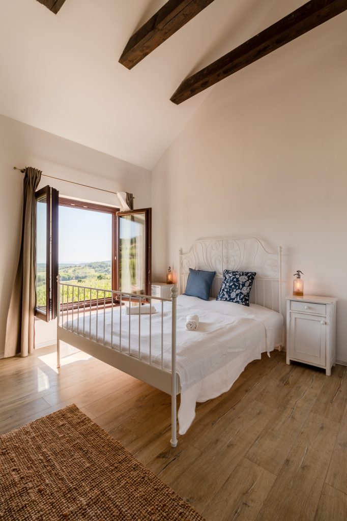 A Nest Cottage kétágyas szobája fa mennyezeti gerendákkal és kilátással a szőlőkre